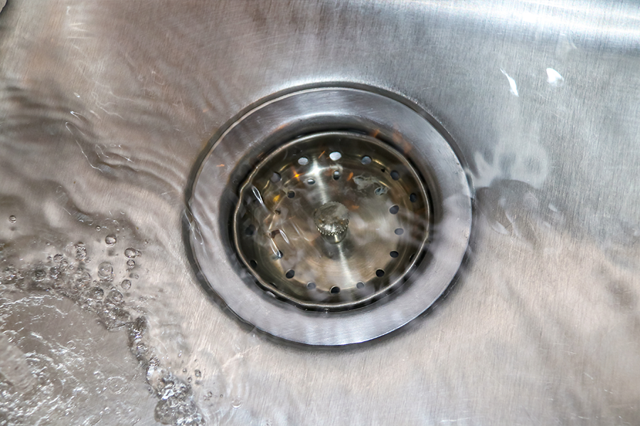 A metal sink stopper sitting inside a kitchen drain in Highland, Illinois.